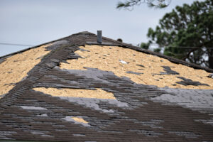 Wind damaged house roof with missing asphalt shingles after storm in Des Moines. Repair of home rooftop concept.